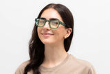 Woman wearing Juno Green, thick rounded, square green sunglasses with yellow lens