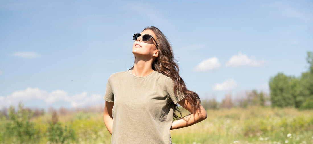 girl wearing sunglasses and looking at the sun in a field