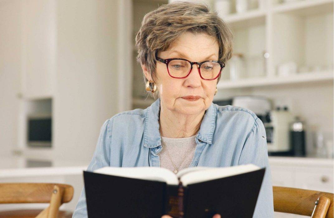 Woman wearing generic reading glasses while reading a book