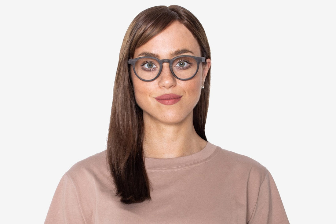 Femme portant des lunettes noires, rétro et rondes en bois de chêne.
