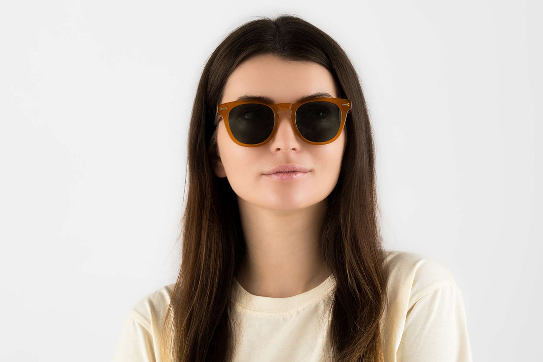 Femme portant des lunettes de soleil orange rondes et carrées avec des verres verts polarisés