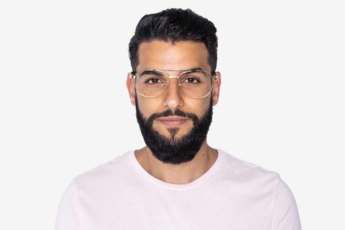 Homme portant des lunettes d'aviateur surdimensionnées et dorées.