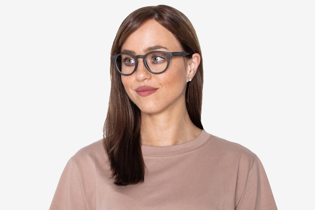 Femme portant des lunettes noires, rétro et rondes en bois de chêne.