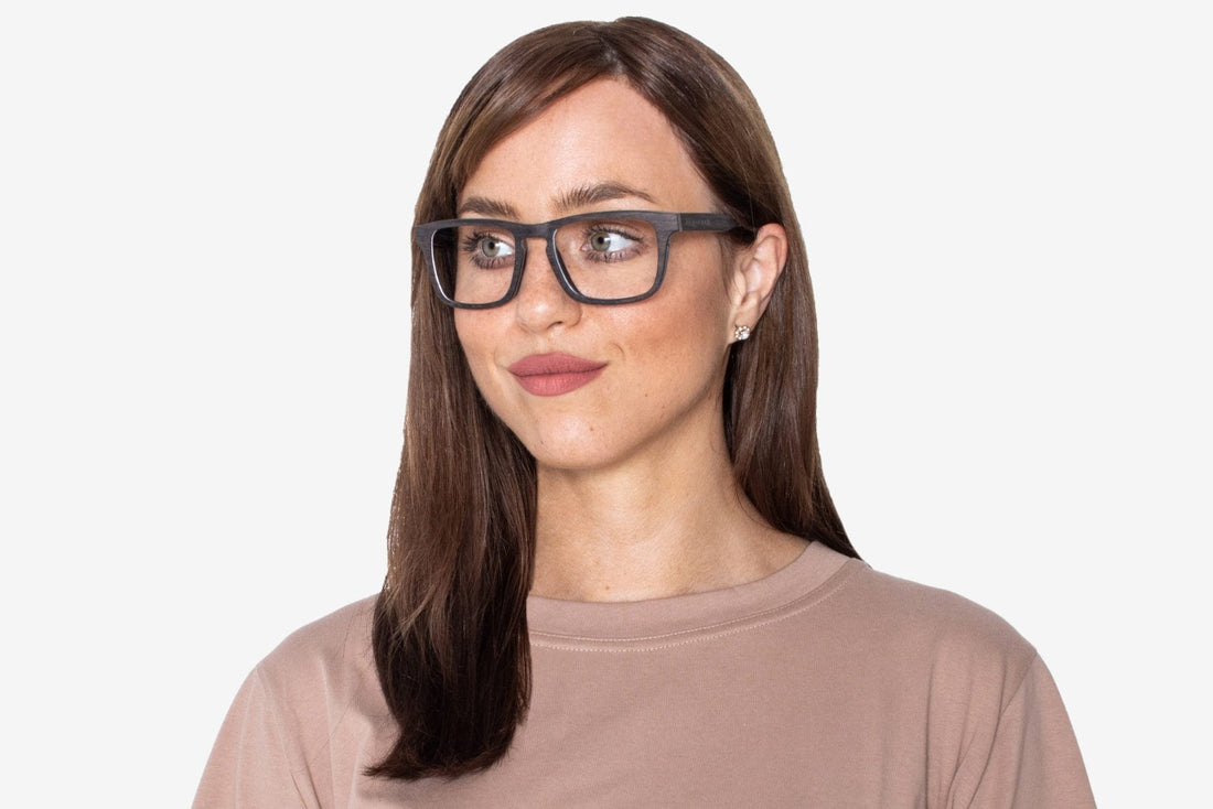 Femme portant des lunettes noires, rectangulaires, en bois de chêne noir.