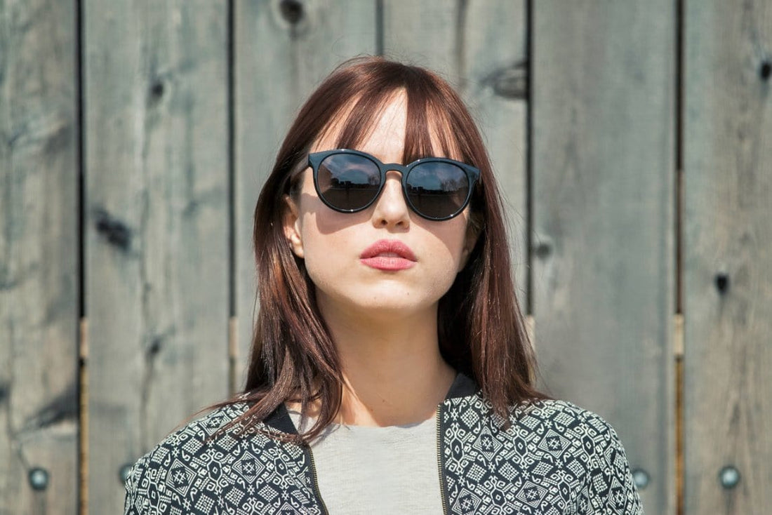 Femme portant des lunettes de soleil Luxy, noires, rondes et polarisées